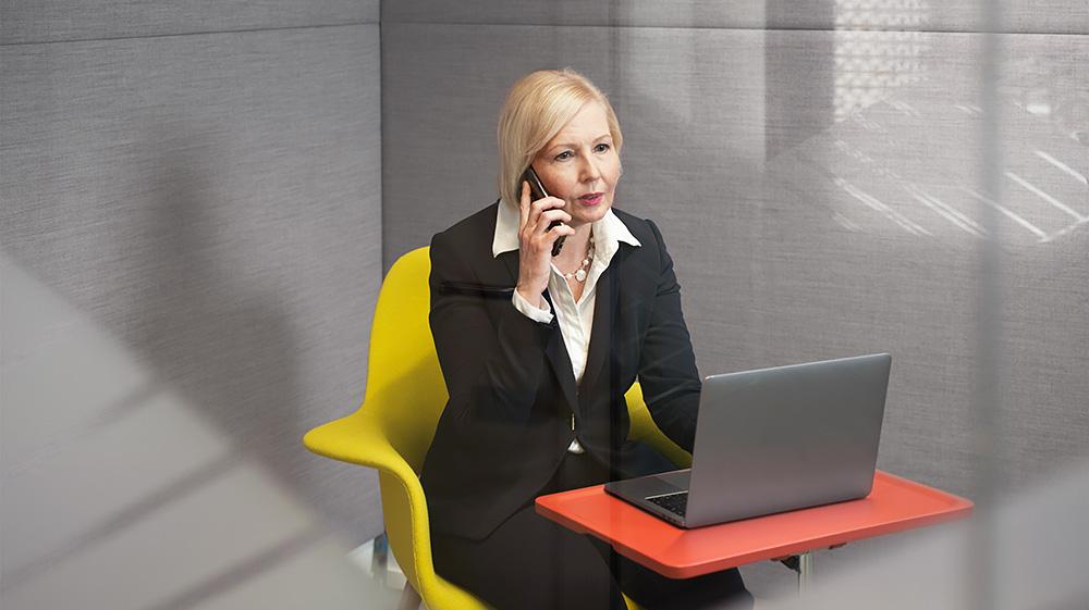 En kvinna vid datorn pratar i telefon.
